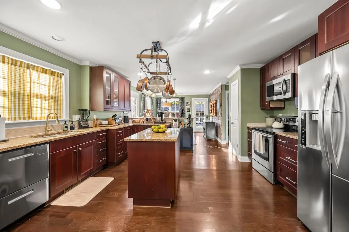 Spotless, professionally cleaned kitchen ready for guests, featuring polished hardwood floors, gleaming stainless steel appliances, dark wood cabinets, and an organized center island.